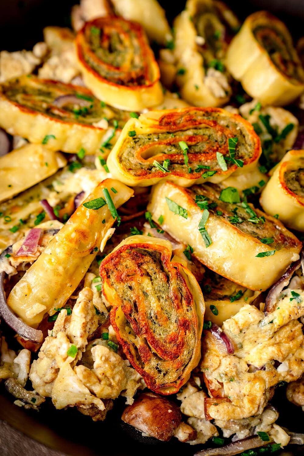 Angebratene Maultaschen in einer Pfanne mit Zwiebeln und Ei und Kräutern