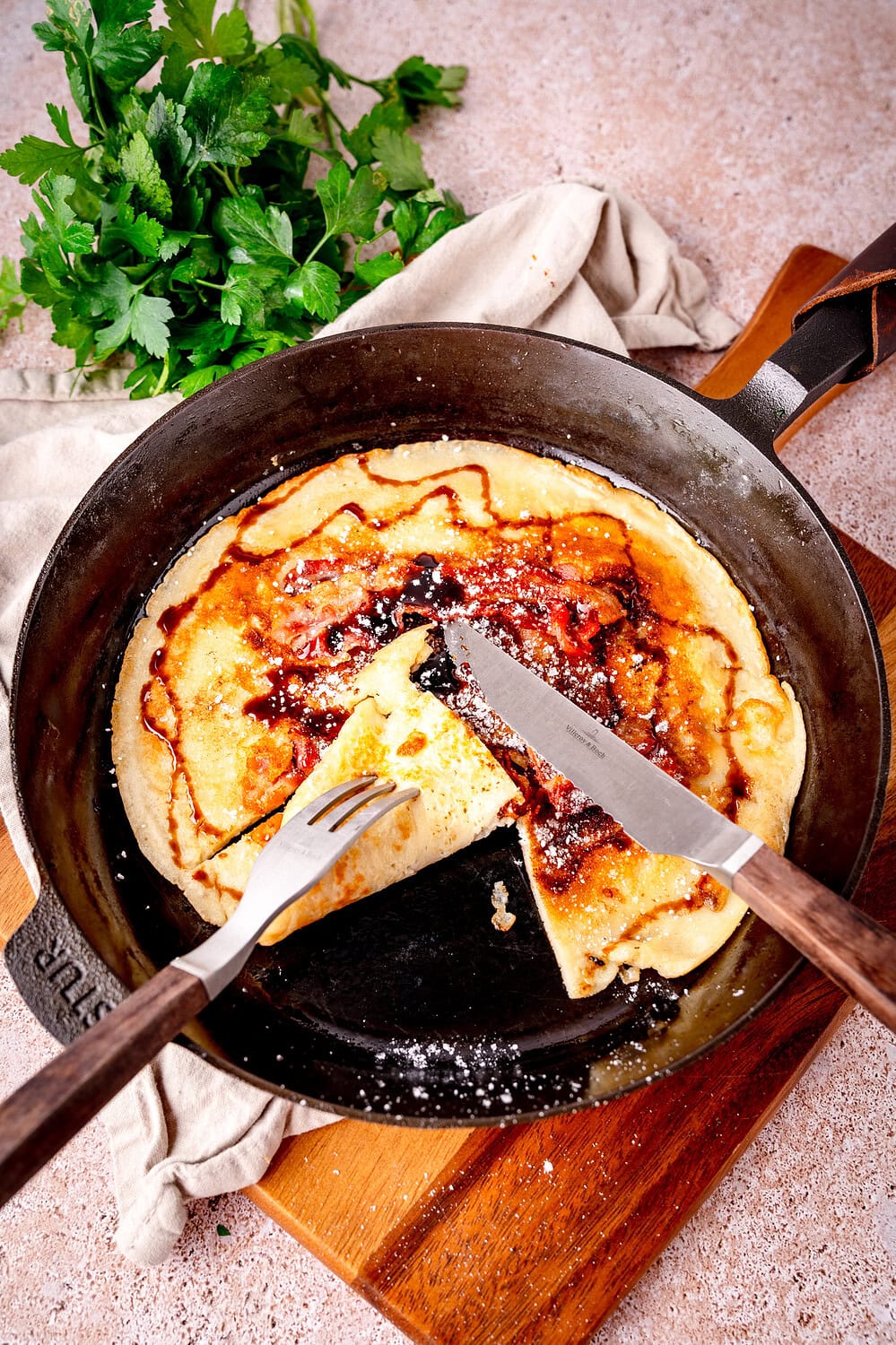 Frisch gebratener Pfannkuchen in der Gusspfanne mit Speck und Zuckerrübensirup.
