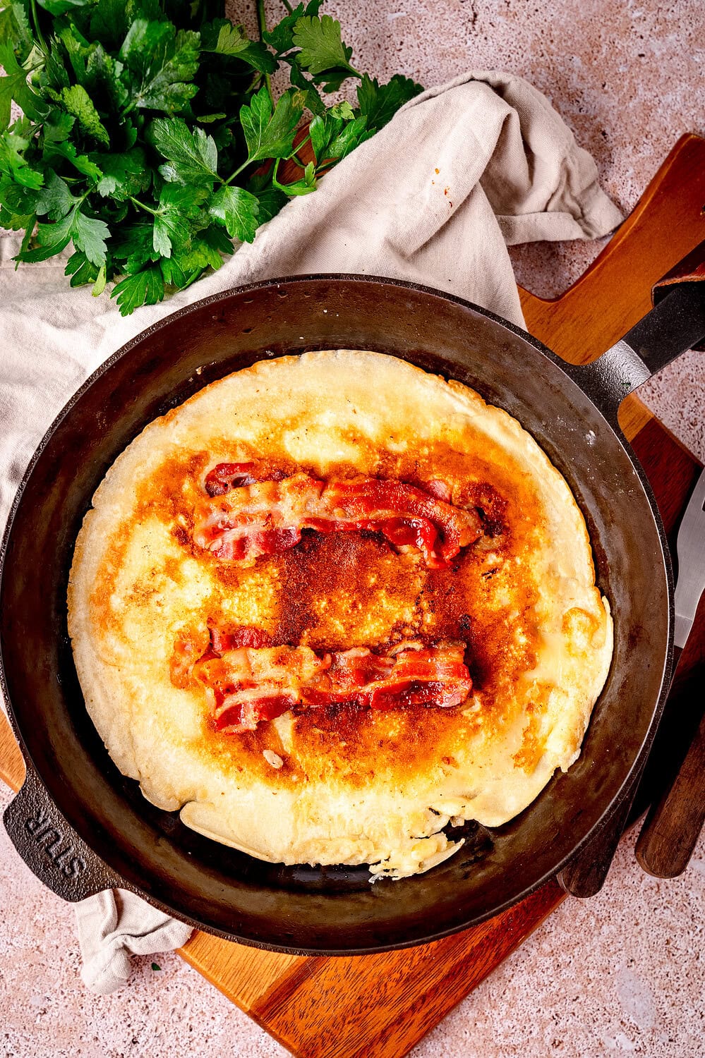 Holländischer Speckpfannkuchen, in der Gußpfanne, mit knusprigem Speck.