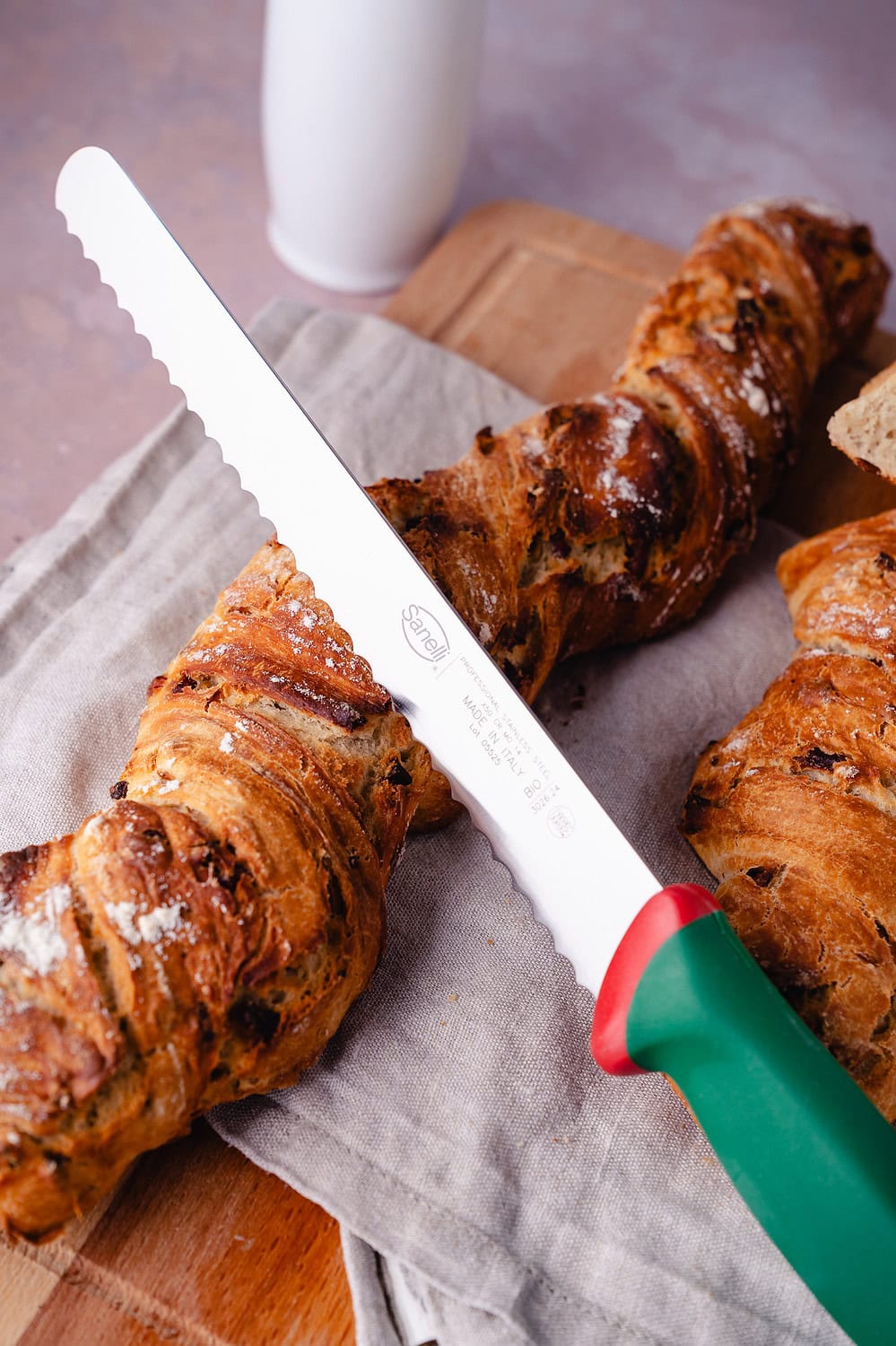 Hochwertiges Brotmesser schneidet frisch gebackene Baguettes auf einem Holzbrett.