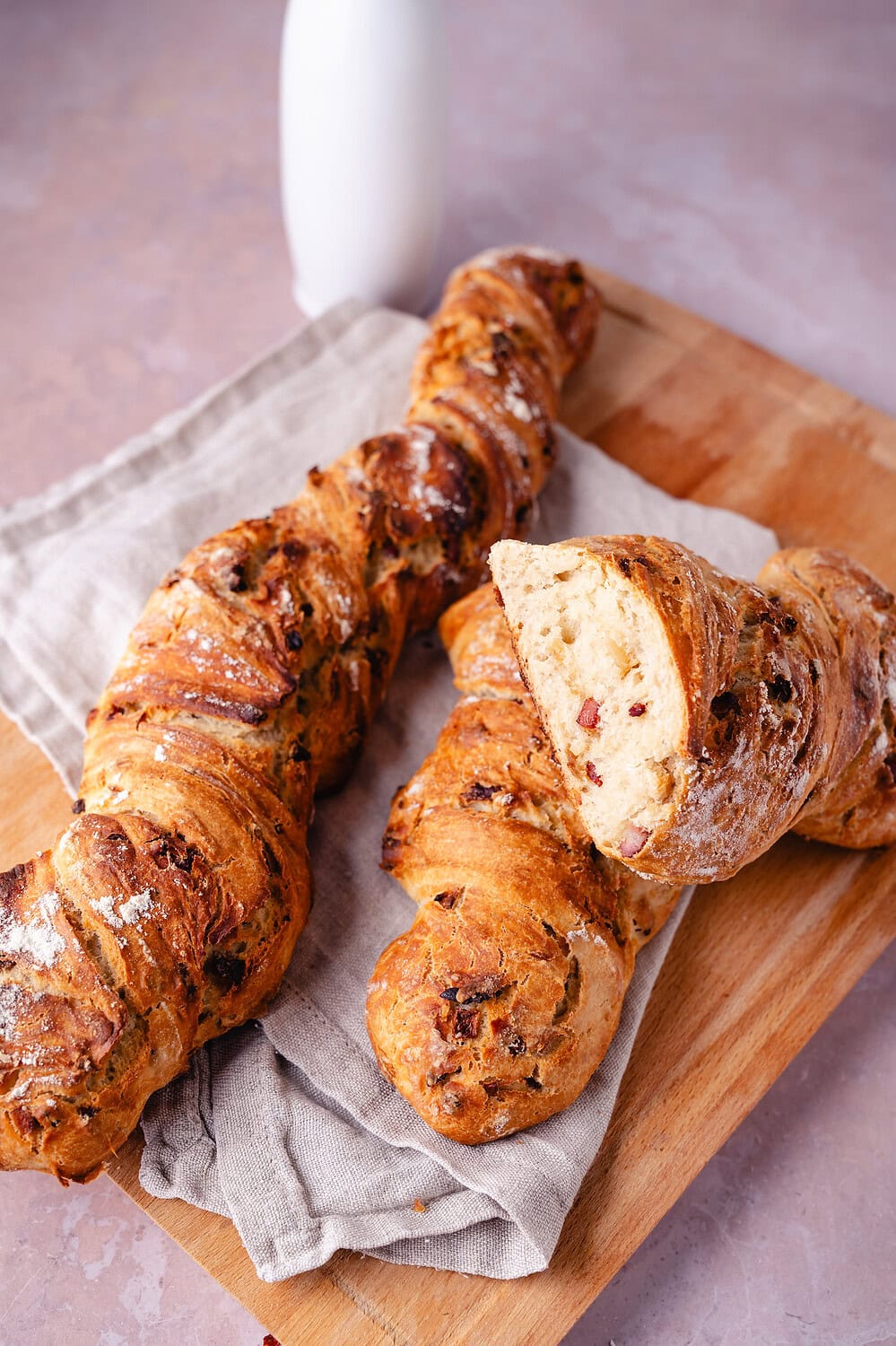 Frisches, knuspriges Zwiebel-Especk-Baguette mit Kräutern auf Holzbrett, perfekt zum Teilen.