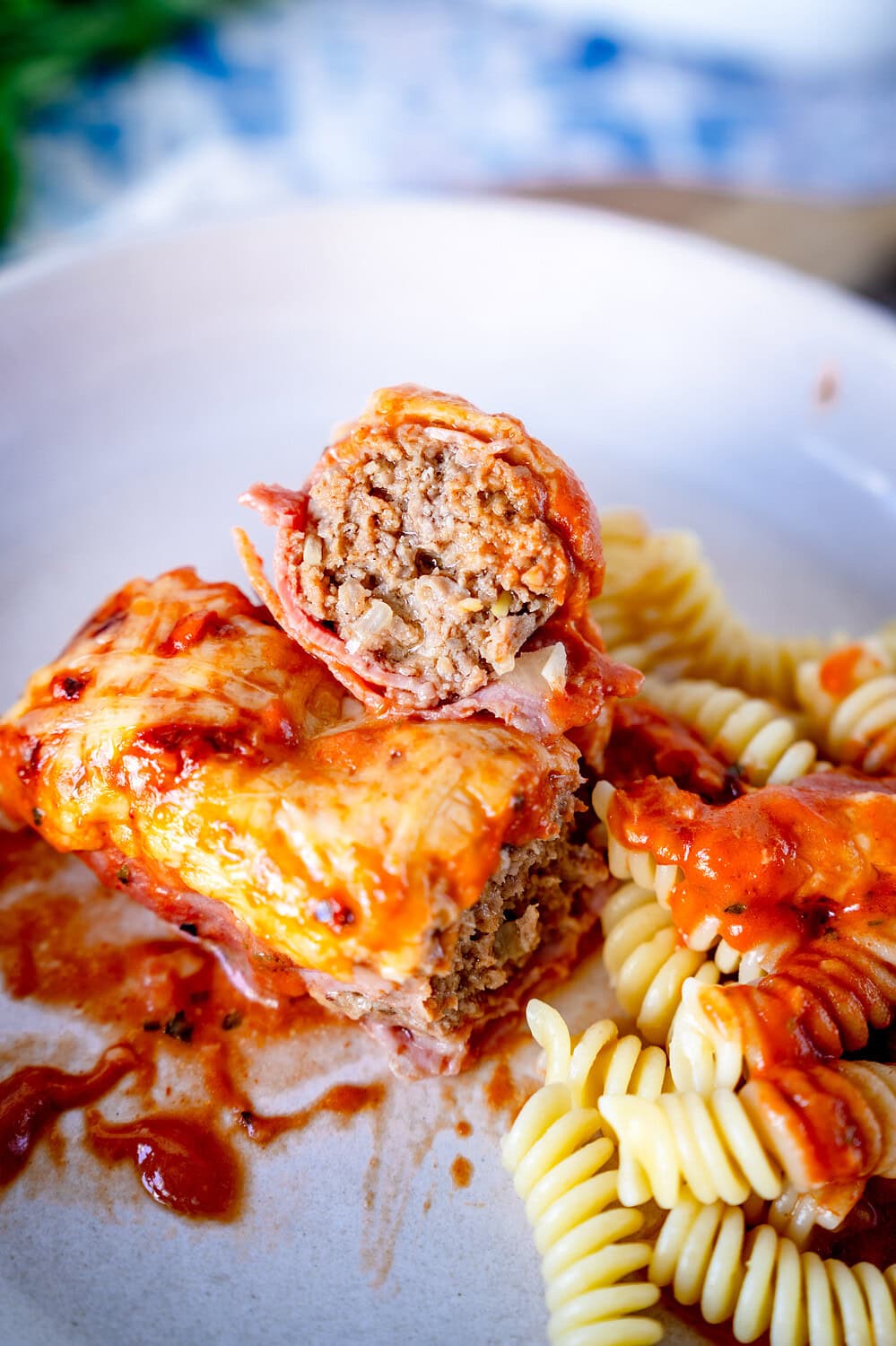 Aufgeschnittene Schinken-Hack-Röllchen auf einem tiefen Teller mit Nudeln und Tomaten-Sahne-Sauce