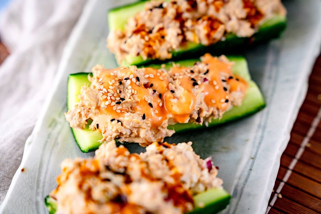 thunfisch-Gurken-SChiffchen im Querformat. Gefüllte Gurke mit Thunfischmayo und Sriracha-Mayo, bestreut mit Sesam 
