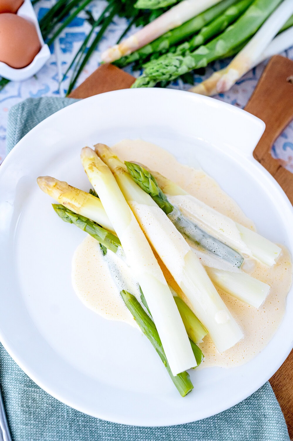 Weißer Teller mit grünem und weißem gekochten Spargel und der Blitz Hollandaise